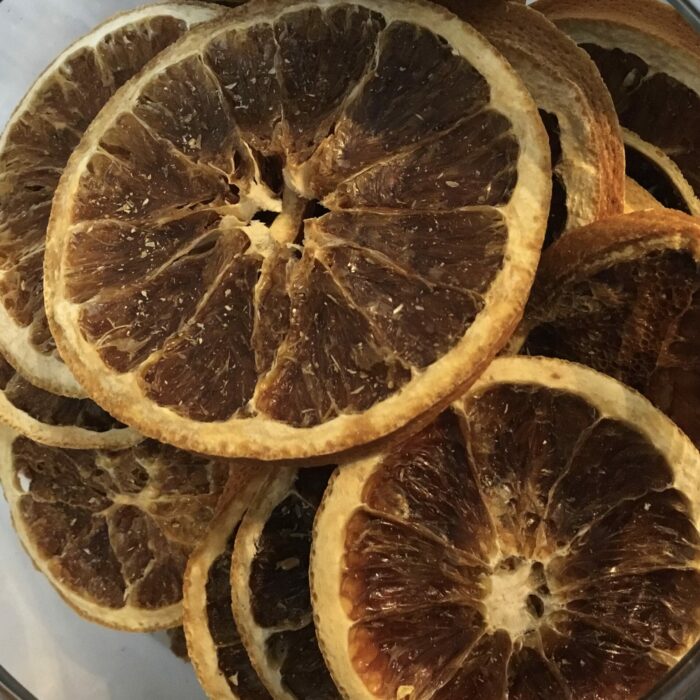 Orange slices are made by thinly slicing oranges and dehydrating them, resulting in a concentrated citrus flavor with a chewy texture and vibrant color.